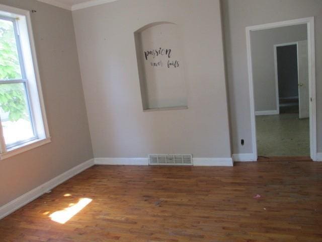 unfurnished room featuring crown molding, a healthy amount of sunlight, and dark hardwood / wood-style floors