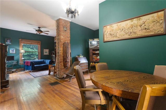 dining space featuring lofted ceiling, hardwood / wood-style floors, and ceiling fan with notable chandelier