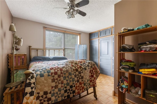 bedroom with ceiling fan, a closet, a textured ceiling, and light parquet floors