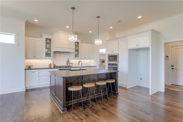 12300 S Hastings St, Olathe, KS 66061 - kitchen featuring built in microwave, white cabinetry, a center island with sink, tasteful backsplash, and dark countertops