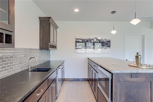 12300 S Hastings St, Olathe, KS 66061 - kitchen featuring stainless steel microwave, tasteful backsplash, dark stone countertops, hanging light fixtures, and dark brown cabinets