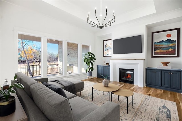 living room featuring an inviting chandelier, a tray ceiling, and light hardwood / wood-style flooring