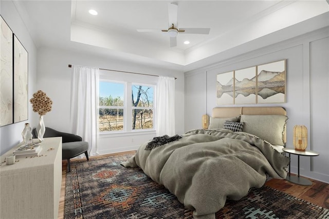 bedroom with hardwood / wood-style floors, a raised ceiling, and ceiling fan