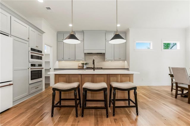 12484 S Barth Rd, Olathe, KS 66061 - kitchen featuring built in refrigerator, light countertops, tasteful backsplash, double oven, and a kitchen bar