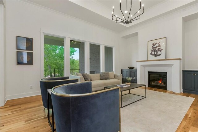 12484 S Barth Rd, Olathe, KS 66061 - living room featuring ornamental molding, a glass covered fireplace, light wood-style flooring, and a chandelier