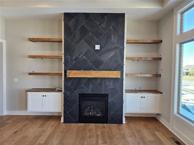 unfurnished living room featuring plenty of natural light, light wood-type flooring, and a fireplace