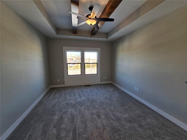 carpeted spare room with a raised ceiling and ceiling fan