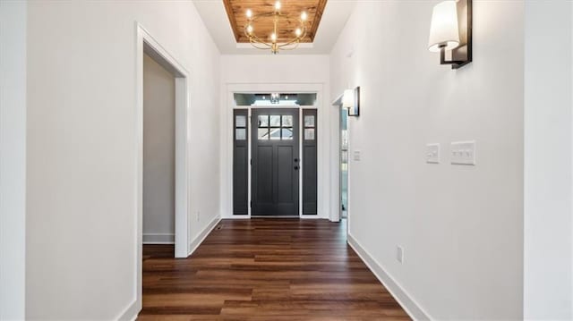 entrance foyer with a tray ceiling, dark hardwood / wood-style floors, and a notable chandelier