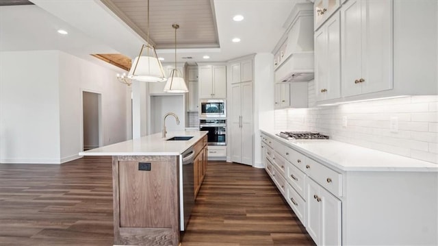 kitchen featuring sink, stainless steel appliances, a center island with sink, white cabinets, and custom range hood