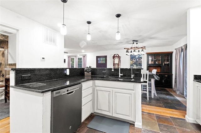 kitchen with dark stone counters, white cabinetry, pendant lighting, and dishwasher