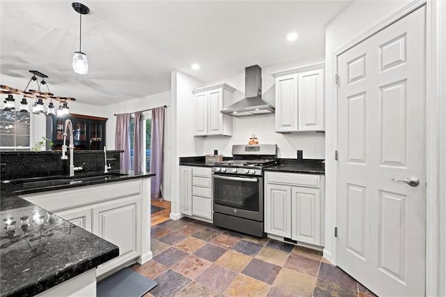 kitchen featuring white cabinets, wall chimney exhaust hood, stainless steel range with gas stovetop, sink, and pendant lighting