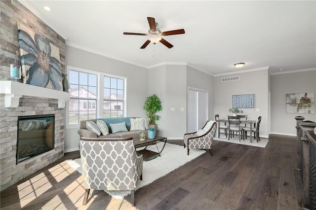 living room with dark wood-type flooring, a large fireplace, crown molding, and ceiling fan