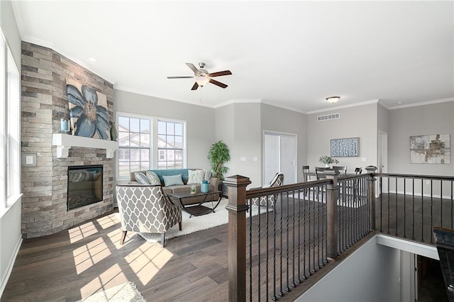 living room featuring ornamental molding, dark hardwood / wood-style floors, ceiling fan, and a fireplace