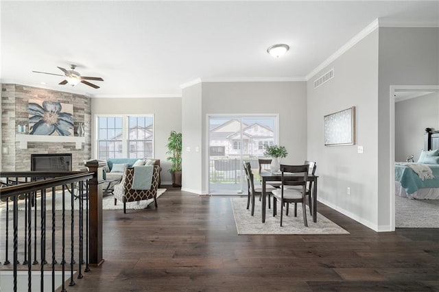 dining room with crown molding, ceiling fan, a fireplace, and dark hardwood / wood-style flooring