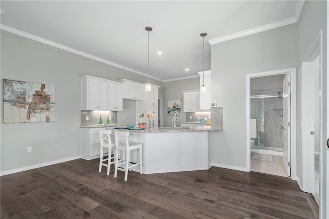 kitchen featuring pendant lighting, dark wood-type flooring, white cabinetry, backsplash, and light stone counters