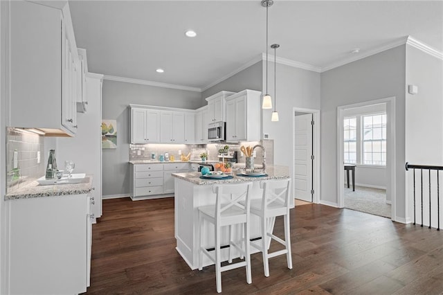 kitchen with pendant lighting, dark hardwood / wood-style floors, crown molding, and white cabinets