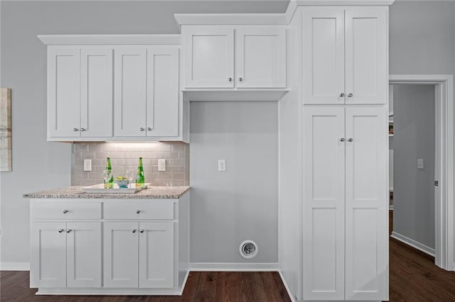 kitchen with white cabinetry, dark hardwood / wood-style flooring, light stone countertops, and tasteful backsplash