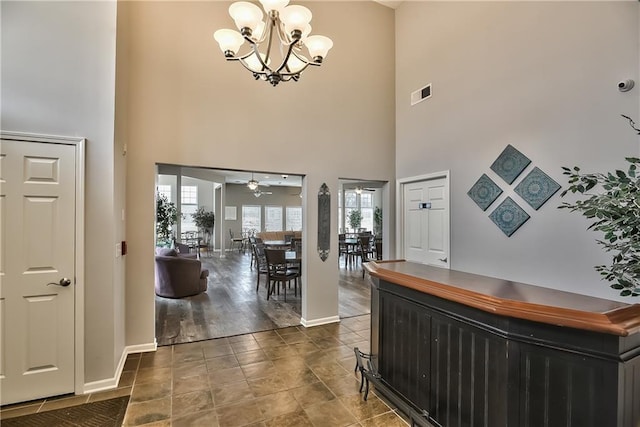 entryway featuring a towering ceiling and ceiling fan with notable chandelier