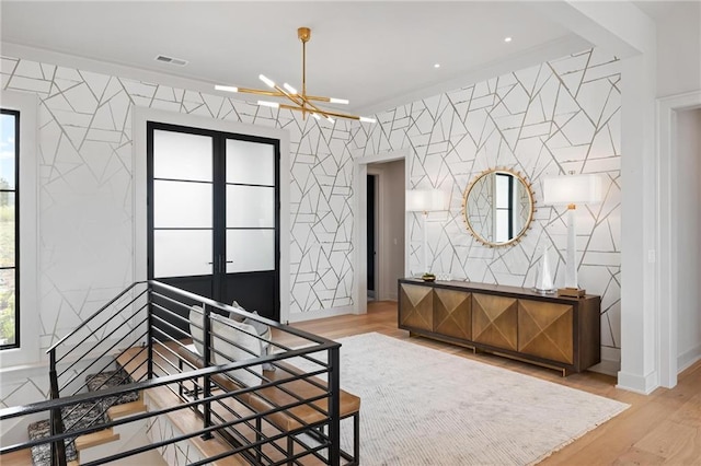 bedroom with a chandelier, wood finished floors, visible vents, baseboards, and french doors