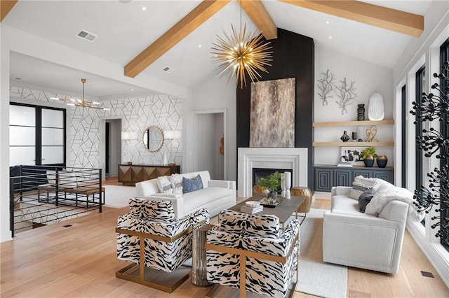 living area featuring visible vents, a fireplace with raised hearth, wood finished floors, vaulted ceiling with beams, and a chandelier