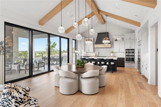 dining space featuring an inviting chandelier, high vaulted ceiling, beamed ceiling, and light hardwood / wood-style floors