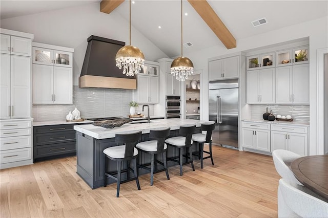 kitchen featuring beamed ceiling, tasteful backsplash, appliances with stainless steel finishes, and custom range hood