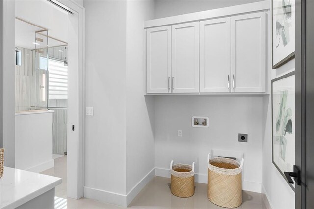 clothes washing area featuring hookup for an electric dryer, cabinets, hookup for a washing machine, and light tile patterned floors