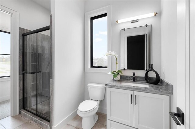 bathroom with a shower with shower door, vanity, tile patterned floors, and toilet