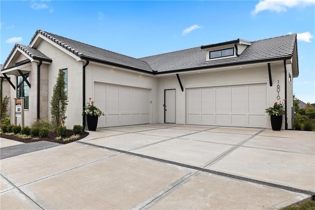 view of side of home with an attached garage, driveway, a tile roof, and stucco siding