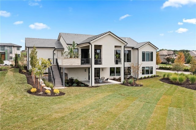 rear view of property with a patio, stairs, a yard, a tiled roof, and stucco siding