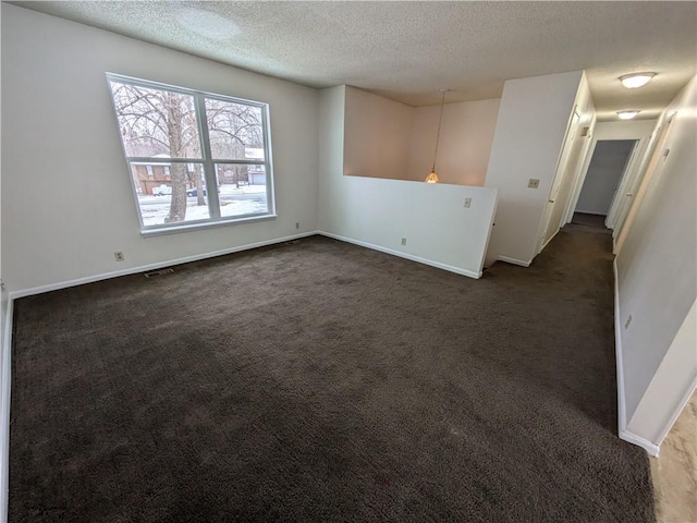 unfurnished room with dark carpet and a textured ceiling