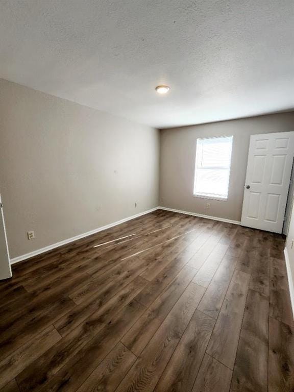 empty room with a textured ceiling and dark hardwood / wood-style floors