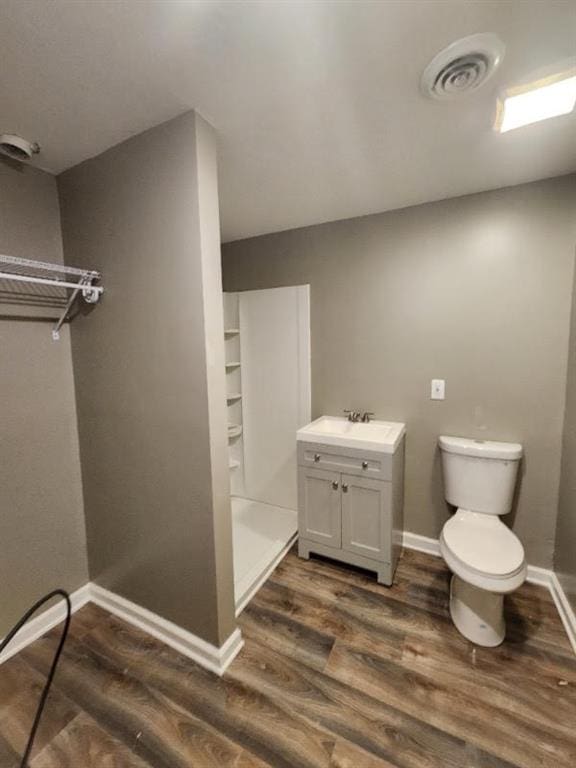 bathroom featuring walk in shower, vanity, toilet, and hardwood / wood-style flooring