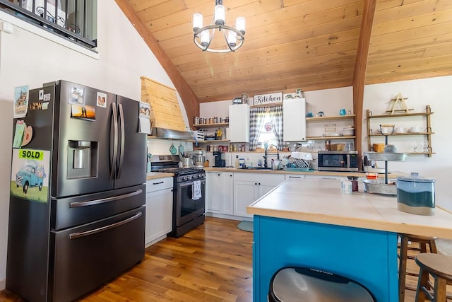 kitchen featuring a chandelier, light hardwood / wood-style flooring, appliances with stainless steel finishes, lofted ceiling, and white cabinets