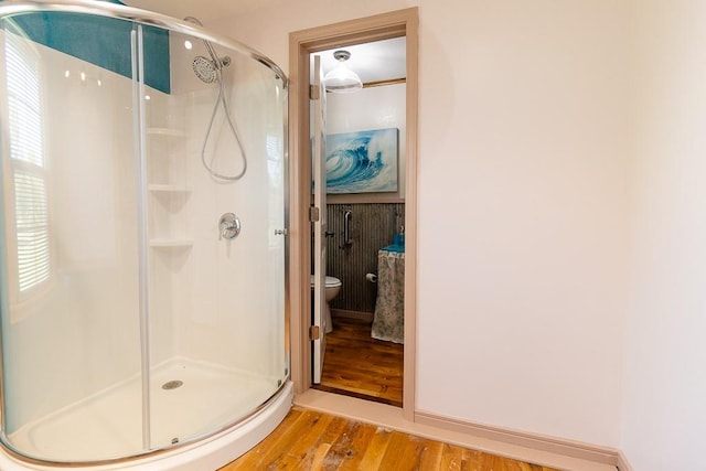 bathroom with toilet, hardwood / wood-style flooring, an enclosed shower, and a wealth of natural light