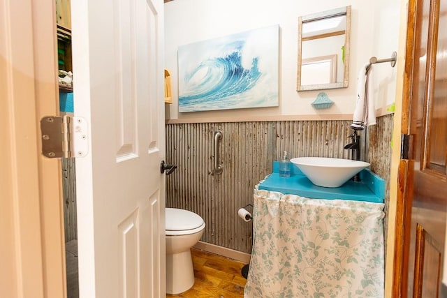 bathroom with vanity, toilet, hardwood / wood-style flooring, and wooden walls