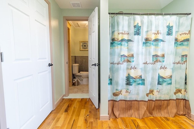 bathroom featuring toilet, a shower with shower curtain, and hardwood / wood-style floors