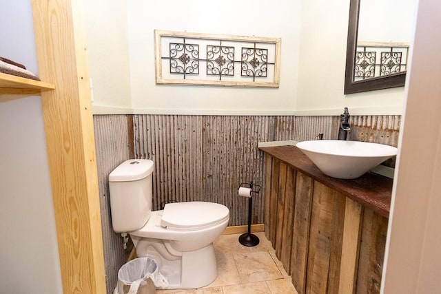 bathroom with tile patterned flooring, vanity, toilet, and wooden walls