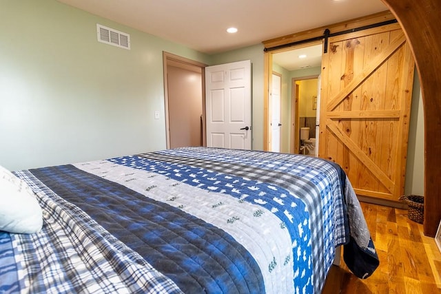 bedroom with a barn door and hardwood / wood-style flooring