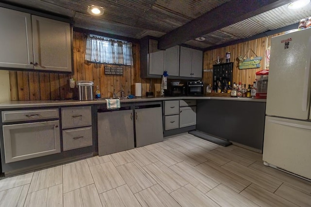 kitchen with wood walls, white fridge, gray cabinetry, and beamed ceiling