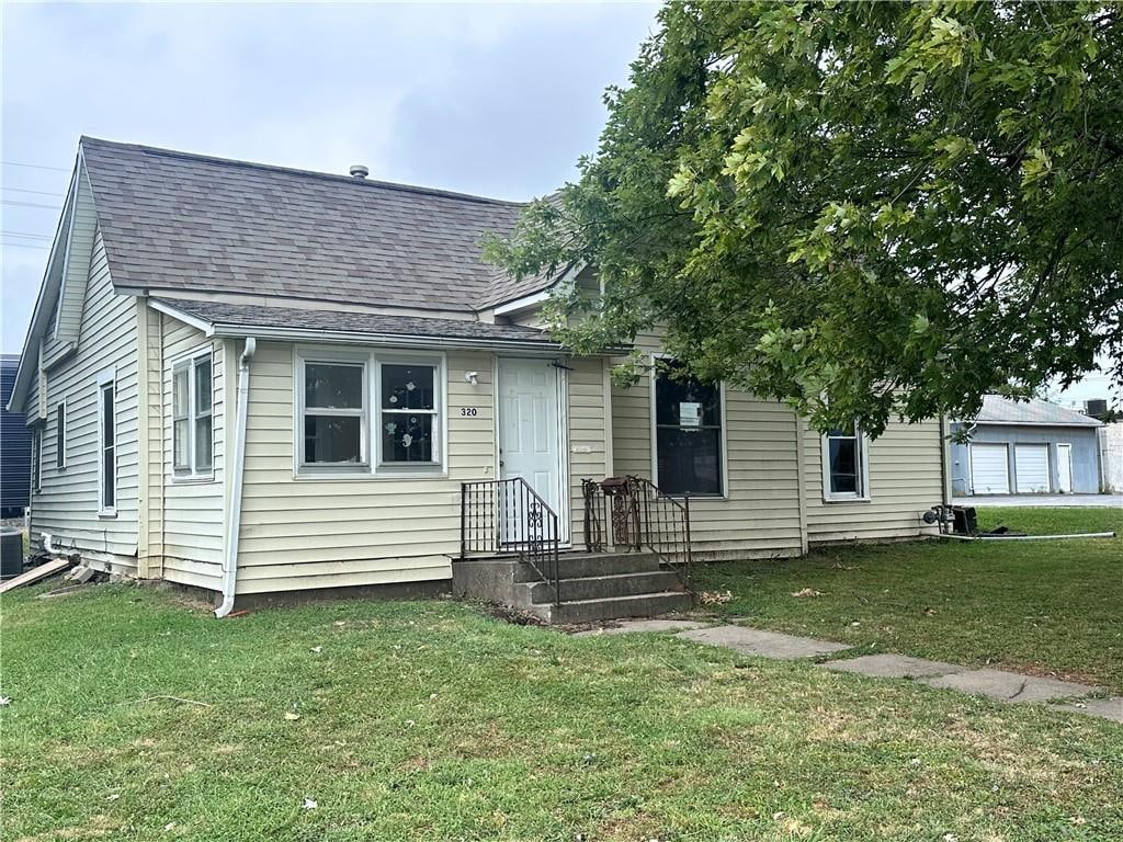 bungalow-style home with central air condition unit and a front lawn