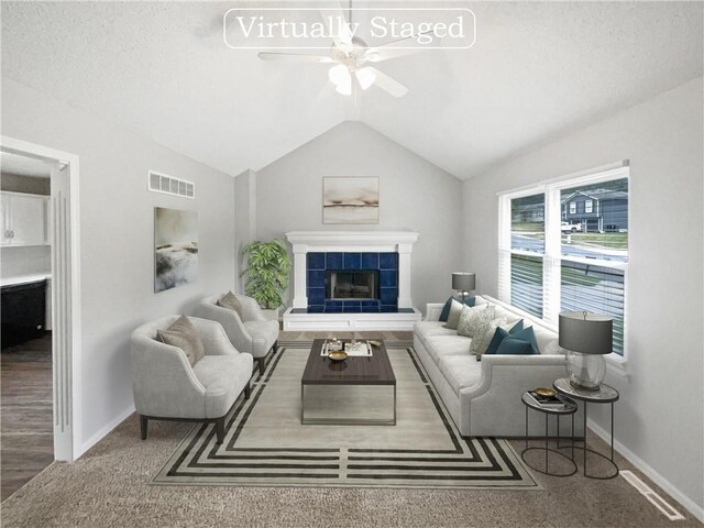 living room featuring a textured ceiling, ceiling fan, hardwood / wood-style flooring, a fireplace, and vaulted ceiling