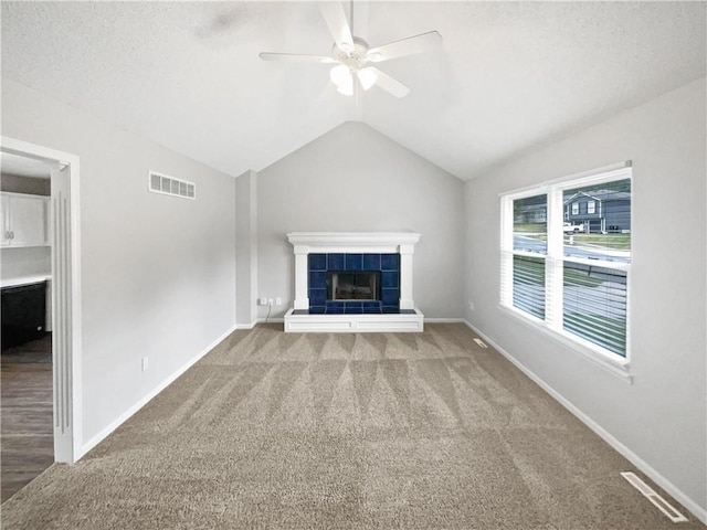 unfurnished living room featuring ceiling fan, lofted ceiling, carpet flooring, and a tile fireplace