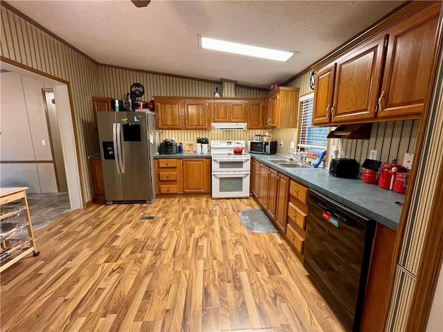 kitchen featuring a textured ceiling, appliances with stainless steel finishes, vaulted ceiling, sink, and light hardwood / wood-style flooring