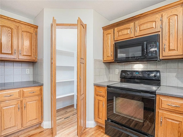 kitchen featuring black appliances, baseboards, light wood finished floors, and backsplash