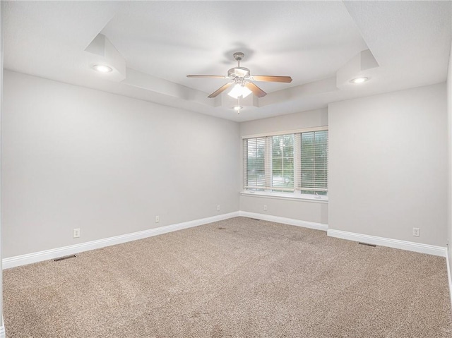 carpeted spare room with a tray ceiling, recessed lighting, a ceiling fan, and baseboards