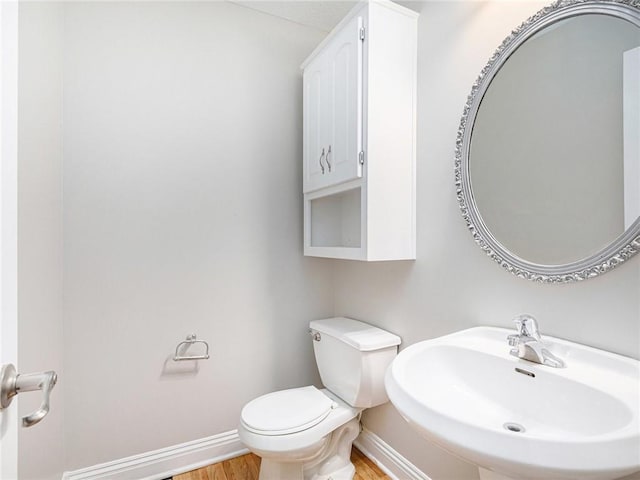 bathroom featuring wood finished floors, a sink, toilet, and baseboards