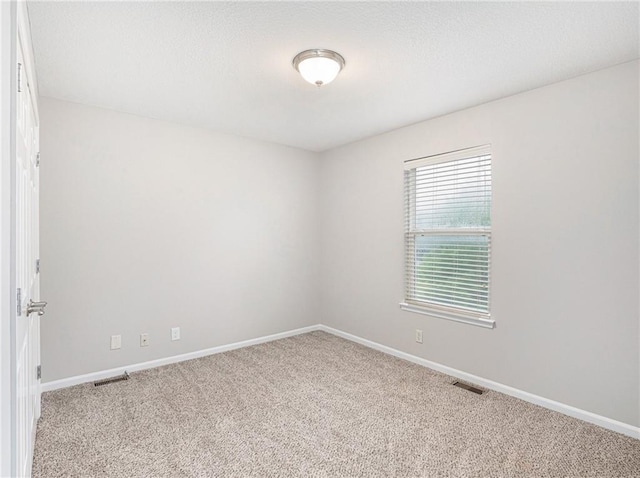 carpeted empty room with visible vents and baseboards