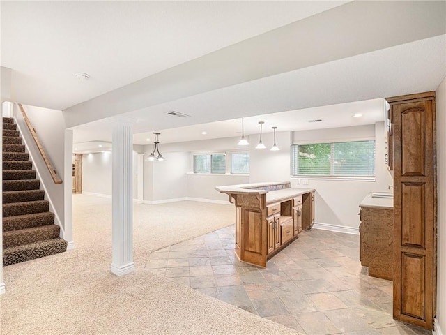 kitchen featuring pendant lighting, brown cabinets, light countertops, open floor plan, and baseboards