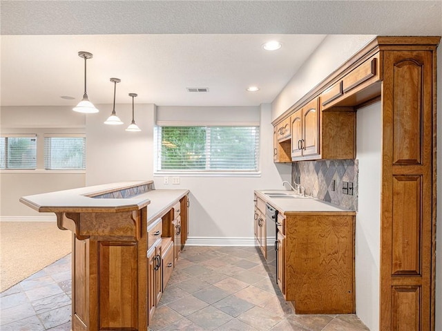 kitchen featuring dishwashing machine, tasteful backsplash, brown cabinetry, and a sink